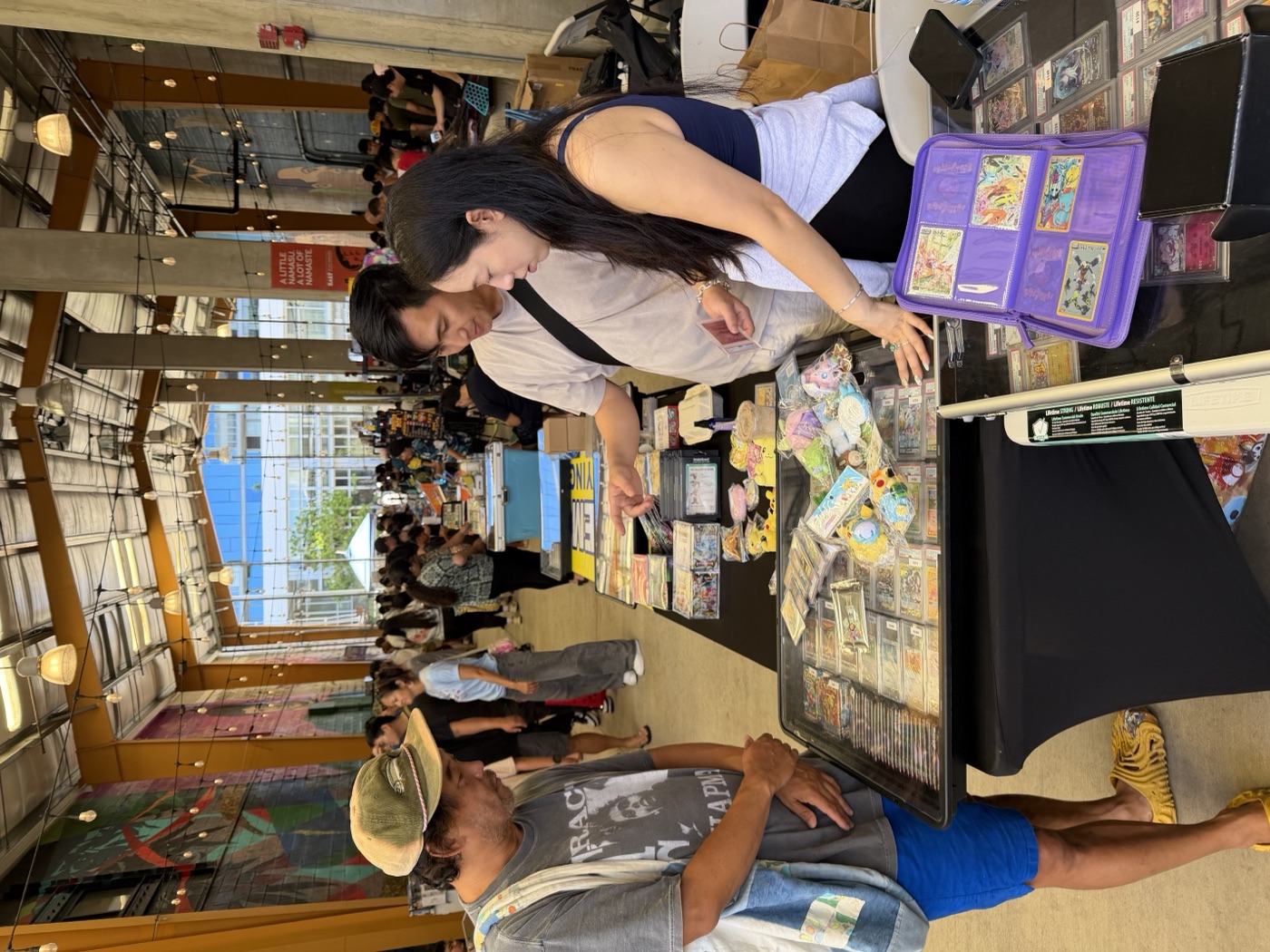 Collectors leaning over a vendor's table digging through cards at Keep It Aloha