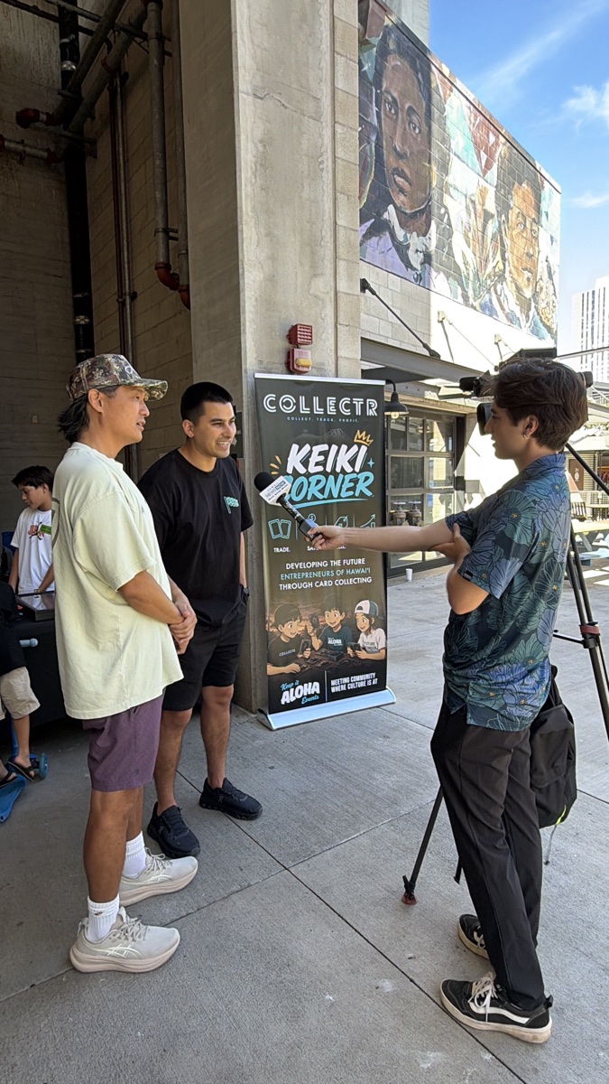 Kamaka and Daniel interviewed next to the Collectr Keiki Corner banner at Keep It Aloha