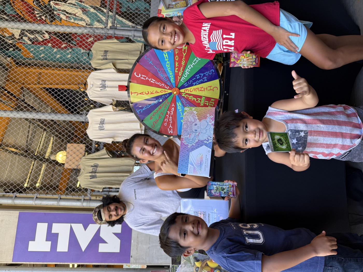 Kids at the Keiki Corner prize wheel holding cards at Keep It Aloha