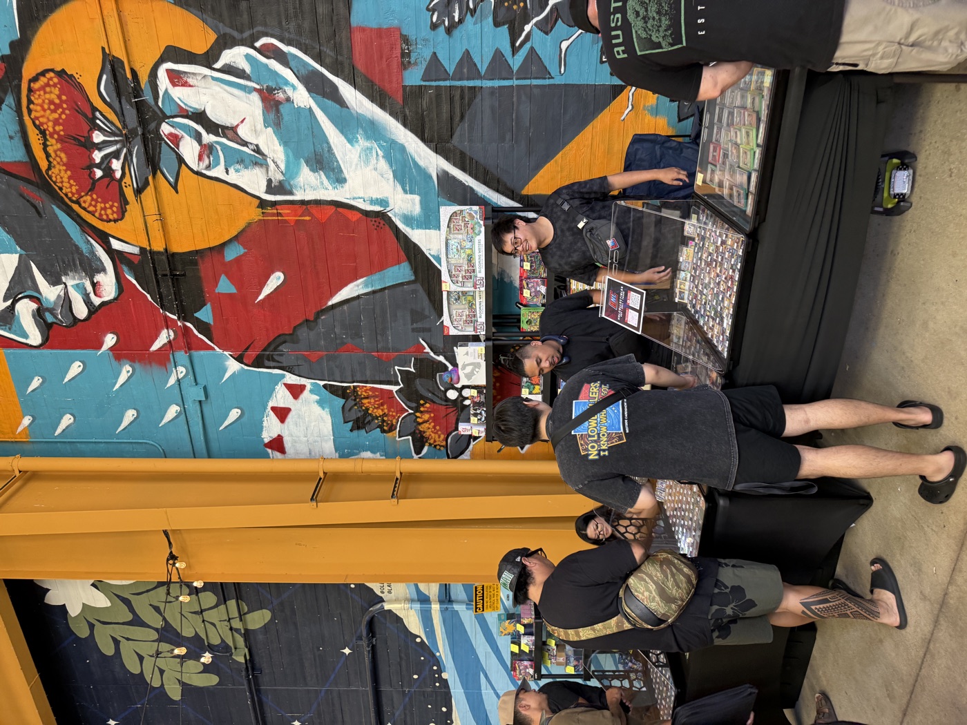 A vendor table stacked with cards set against a bold Kaka'ako mural at SALT