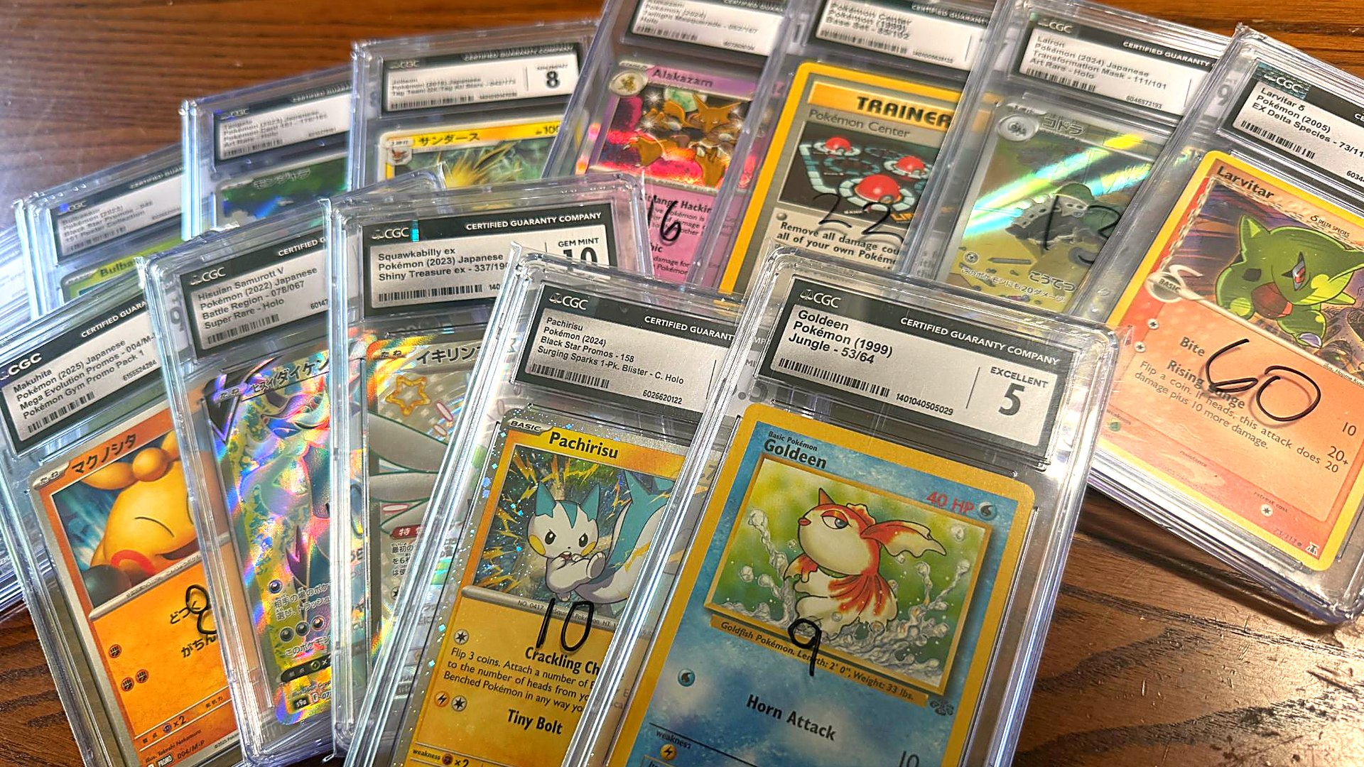 A spread of CGC-graded Pokemon slabs on a table, several marked with handwritten prices